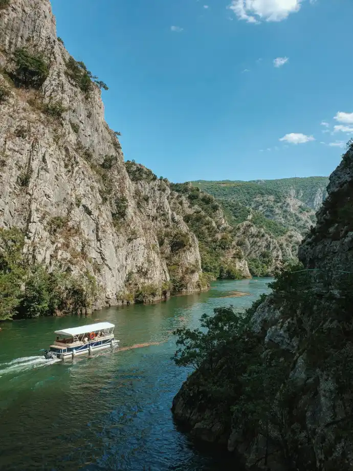 white boat on river near rocky mountain during daytime